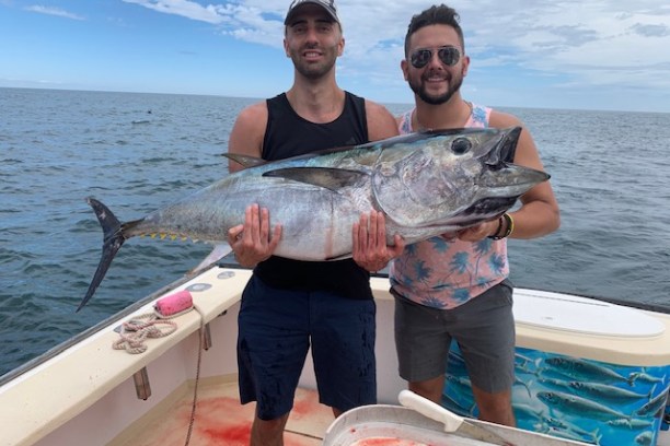 a person holding a fish on a boat in a body of water