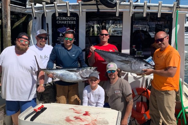 a group of people standing in front of a military man holding a fish