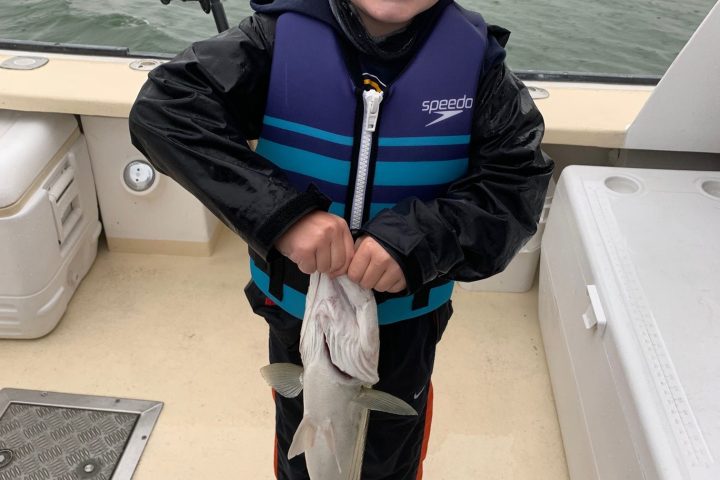 a little boy standing in front of a body of water